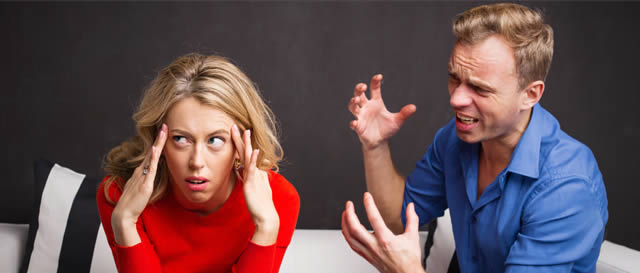 Couple arguing on sofa with lady holding her head Couple arguing on sofa with lady holding her head