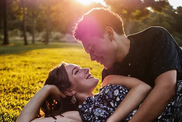 Differences between loving someone and being in love - Man and woman laying on the park grass with sun rays from behind Differences between loving someone and being in love - Man and woman laying on the park grass with sun rays from behind