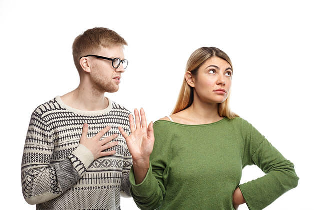 Why Do Men Pull Away - Young man holding hand on his chest with angry girlfriend looking away Why Do Men Pull Away - Young man holding hand on his chest with angry girlfriend looking away