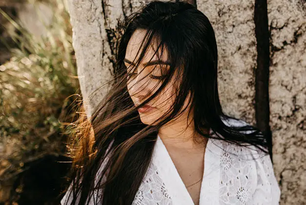 He Doesn't Love Me Back - Sad young lady leaning on a tree outdoors with breeze blowing through her hair