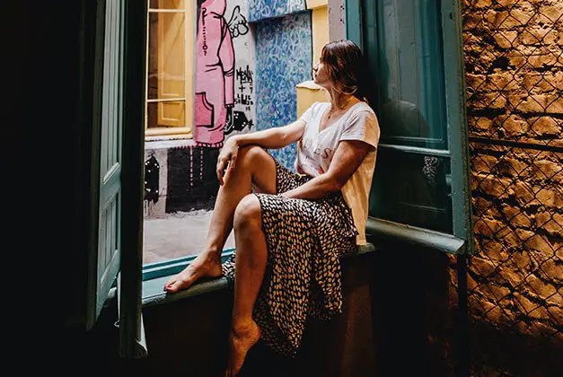 How to Stop Loving a Guy Who Doesn't Love You - Young sad lady sitting alone by a big open window