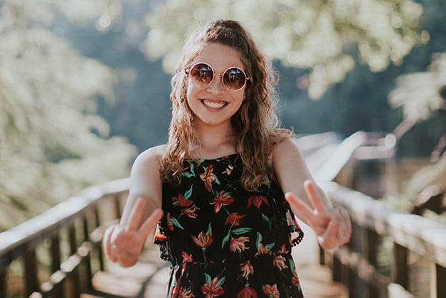 Love and Personal Happiness - Happy young lady in sunglass on a bridge with hands pointing two fingers Love and Personal Happiness - Happy young lady in sunglass on a bridge with hands pointing two fingers
