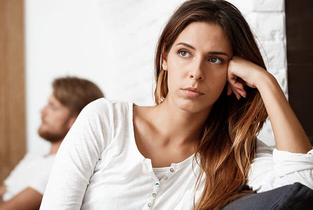 Things You Can Do When He Doesn't Love You Back - Sad and disappointed young lady in thoughts with her boyfriend in the background