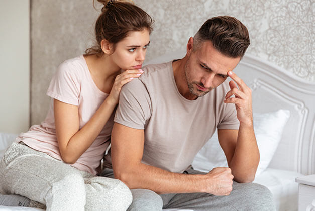 Ways to Save a Struggling Relationship - Young couple sitting on bed with lady calming upset boyfriend