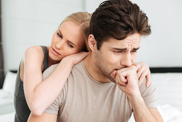 Ways to Stop Loving a Guy Who Doesn't Love You Back - Sad couple sitting on bed with guy deep in thoughts