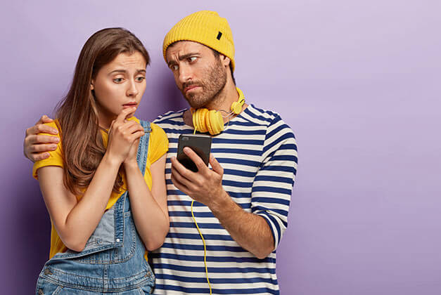 Why Women Cheat - Millennial woman sadly looking at her secret message on smartphone in her spouse's hand Why Women Cheat - Millennial woman sadly looking at her secret message on smartphone in her spouse's hand