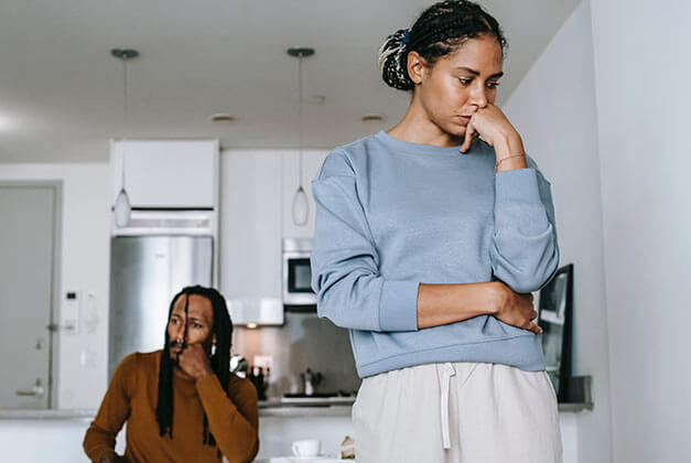 Why Women Cheat - Young sad couple in kitchen with lady thinking while looking down Why Women Cheat - Young sad couple in kitchen with lady thinking while looking down