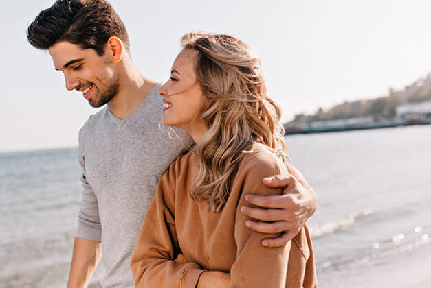 Having Better Communication With Men - Happy blonde woman talking with husband during walk on beach Having Better Communication With Men - Happy blonde woman talking with husband during walk on beach